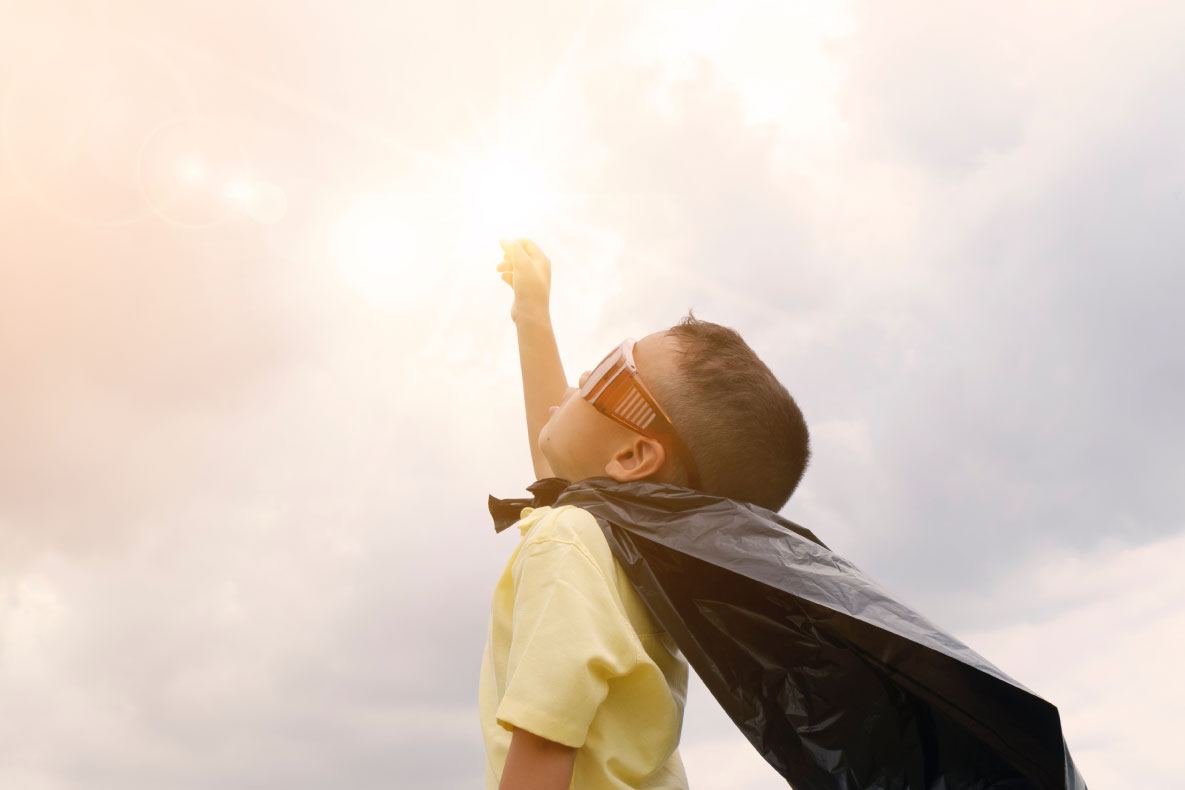 Little boy in a cape dressed as a superhero
