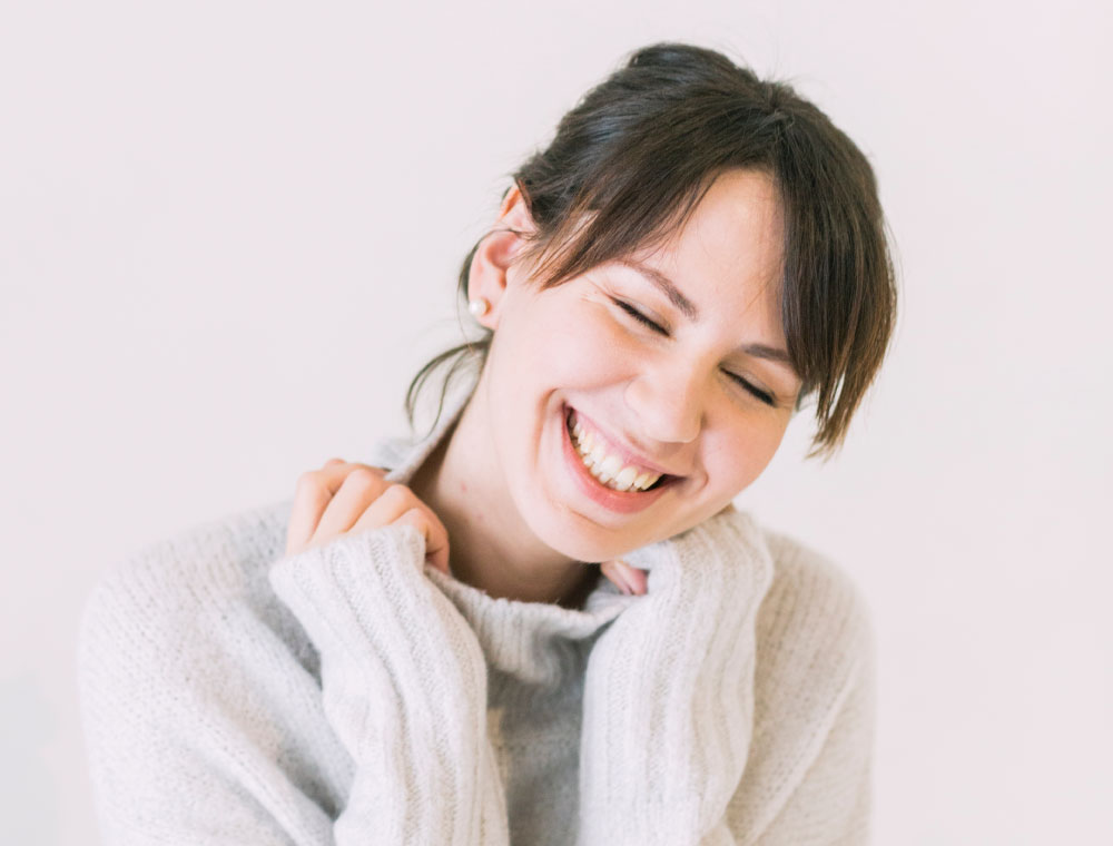 Jeune femme brune en pull à col roulé souriant