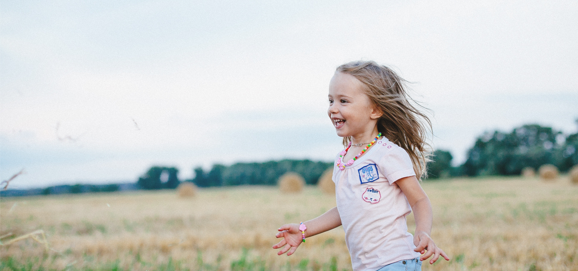 Junges Mädchen, das lächelnd durch ein Feld rennt