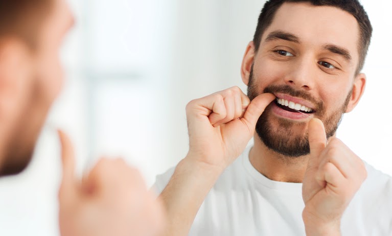 Junger Mann benutzt Zahnseide mit edelwhite Supersoft Zahnseide